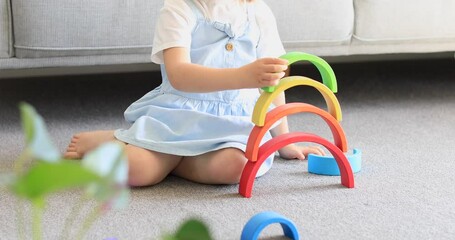 A cute girl is playing an educational game with a wooden rainbow. 
