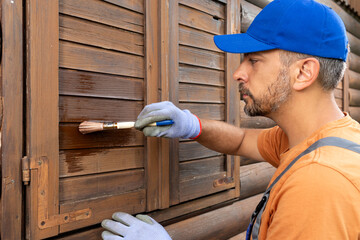 Protecting wooden house exterior with applying stain or paint.