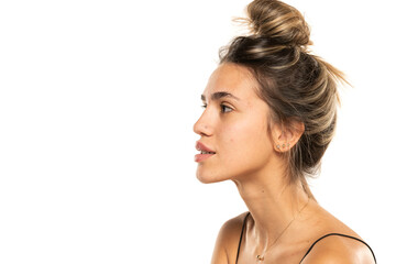 woman with messy loose bun and no makeup on a white studio background. side profile view