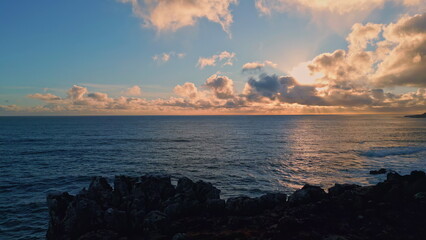 Drone amazing evening seascape on rocky shore. Sunset light reflecting in ocean