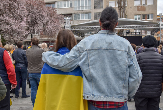 A girl draped in a Ukrainian flag at a protest against the war in Ukraine. A young couple supports Ukraine.