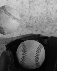 Old vintage black and white baseball art in vertical view with old balls by glove.