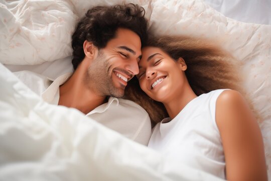 Headshot top view of multi ethnic young couple cuddling together in bed in the morning