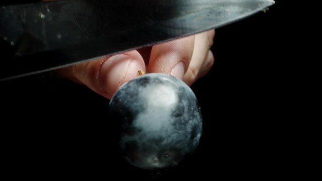 I cut black grape berries with a knife, in slow motion, macro zoom.