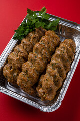Lule Kebab Dish for Delivery in Foil Packaging Box on a Red Background