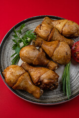 Grilled Chicken Drumsticks on a Gray Plate on a Red Background
