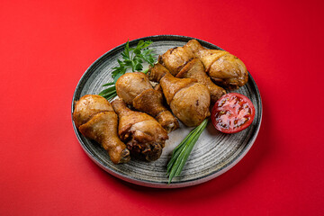 Grilled Chicken Drumsticks on a Gray Plate on a Red Background