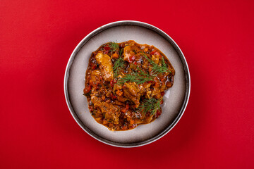 Ragout on a Round Gray Plate on a Red Background