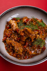Ragout on a Round Gray Plate on a Red Background
