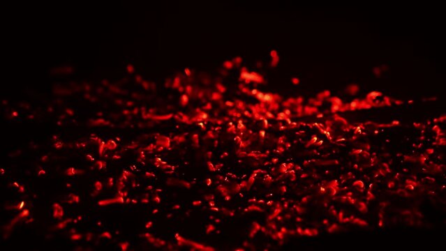 Shimmering Red Light Appearing In The Smoldering Embers. Campfire Burnt Out And The Hot Pieces Of Charcoal Flashing. Close Up. Black Backdrop.