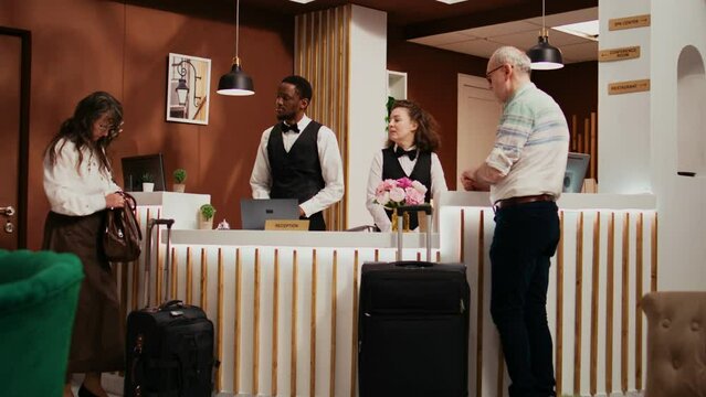 Front Desk Staff Checking Passports For Tourists With Room Reservation At Five Star Hotel, Looking At Id Documents In Reception Lobby. Diverse Employees Assisting Senior Couple.