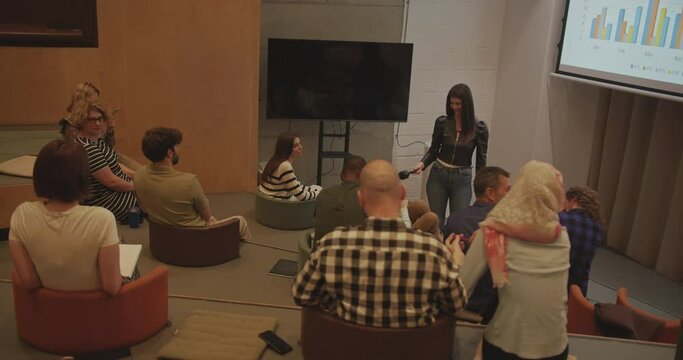 In an amphitheater room during a business seminar, a back view of a group of international and multireligion people engaging in discussions and interactions. The scene embodies the concept of work