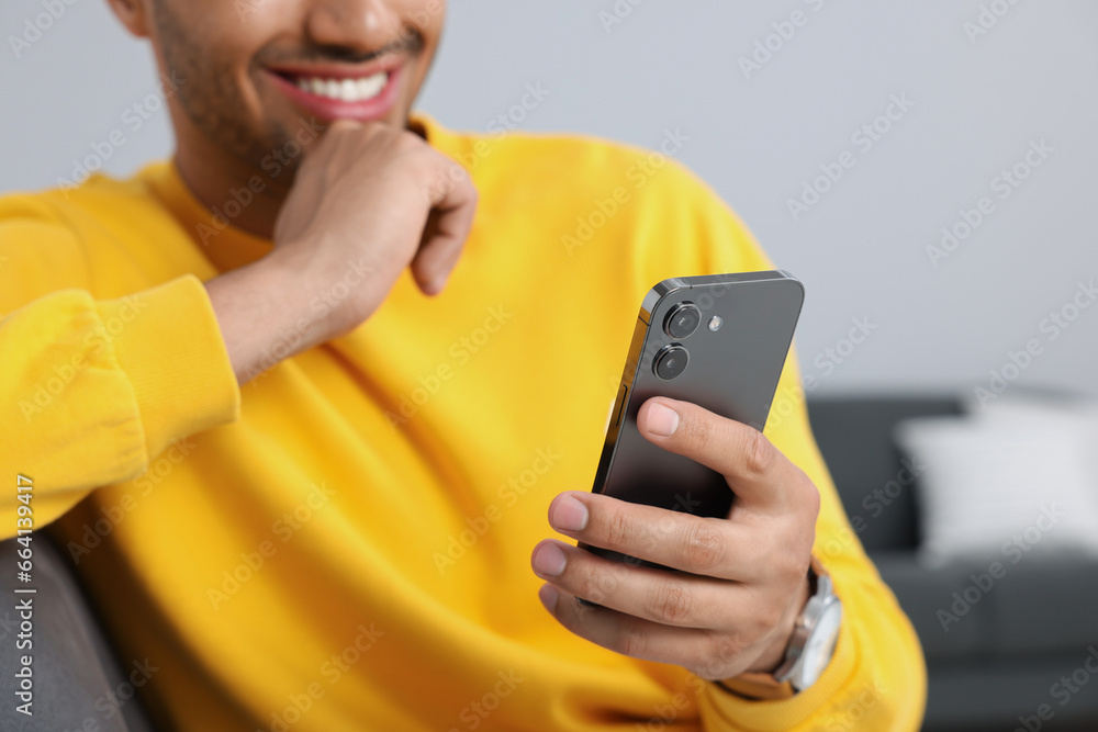 Poster man sending message via smartphone indoors, closeup