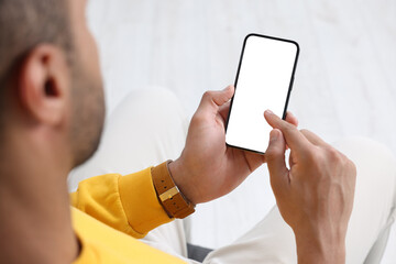 Man using modern mobile phone indoors, closeup