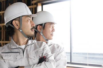 とても使いやすい未来を見上げる腕を組む現場作業員たちのクローズアップ 逆光の中で