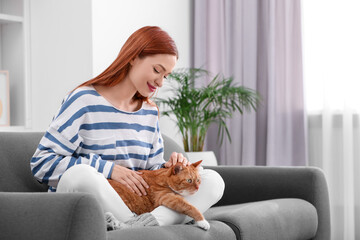 Woman with her cute cat on sofa at home