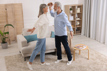 Happy affectionate senior couple dancing at home