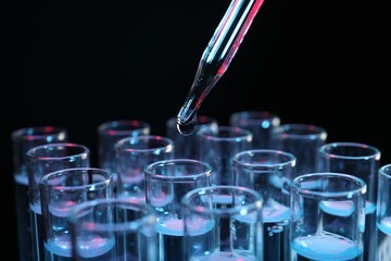 Dripping reagent into test tube on black background, closeup. Laboratory analysis