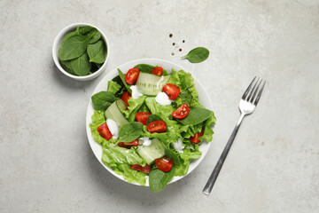 Delicious vegetable salad served on light grey table, flat lay