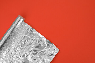Roll of aluminum foil on orange background, top view. Space for text