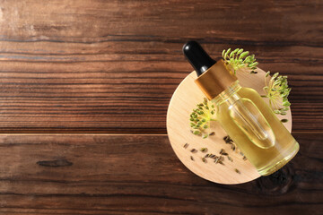 Bottle of essential oil, seeds and fresh dill on wooden table, top view. Space for text
