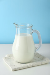 One jug of fresh milk on white table against light blue background