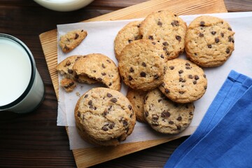 Delicious chocolate chip cookies and milk on wooden table, flat lay
