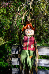 Obraz premium Smiling boy scarecrow leaning against a wood fence, cheerful fall celebration for Halloween and Thanksgiving 