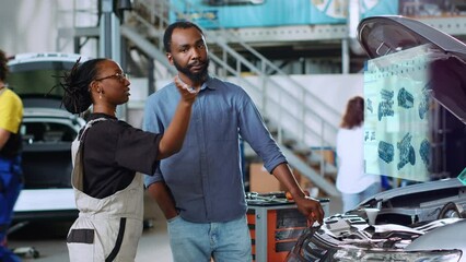 African american mechanic in repair shop using holographic augmented reality to show client defective components inside car. BIPOC garage worker using advanced AR tech to project vehicle parts - Powered by Adobe