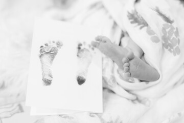 A black and white close-up photo of newborn feet next to his or her footprints at birth 