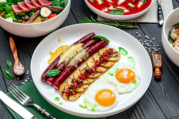 Assorted food set on table, tomato soup with mozzarella, tuna salad, scrambled eggs with sausages