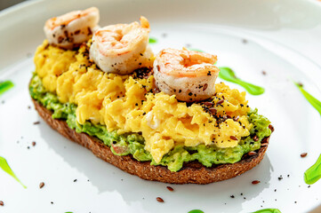 Scrambled on toast with guacamole, shrimp and olives