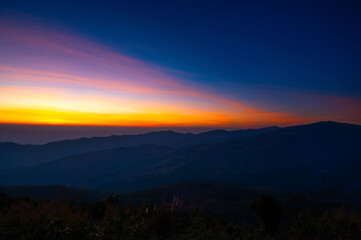 Aerial view sunset , sunrise over dark mountain with fog over the ground.The early evening sun illuminates the mountains and valleys.Dawn the first appearance of light in the sky before sunrise.