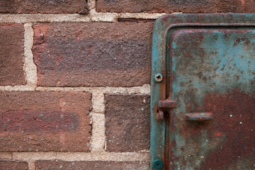 Brick and rusted metal hatch with blue paint