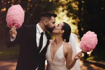 Newlywed couple with cotton candies kissing in park