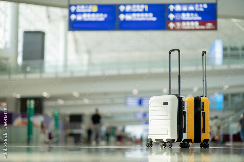 Wall mural Two suitcases in an empty airport hall, traveler cases in the departure airport terminal waiting for the area, vacation concept, blank space for text message or design