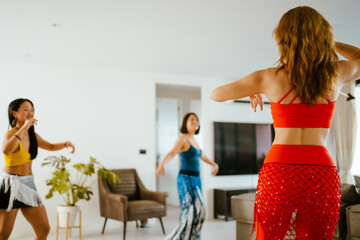 Picture of a group of female friends  performing Belly Dance in beautiful costumes. with fun at their homes, woman dance, Belly dancer in legging and hip scarf dancing.