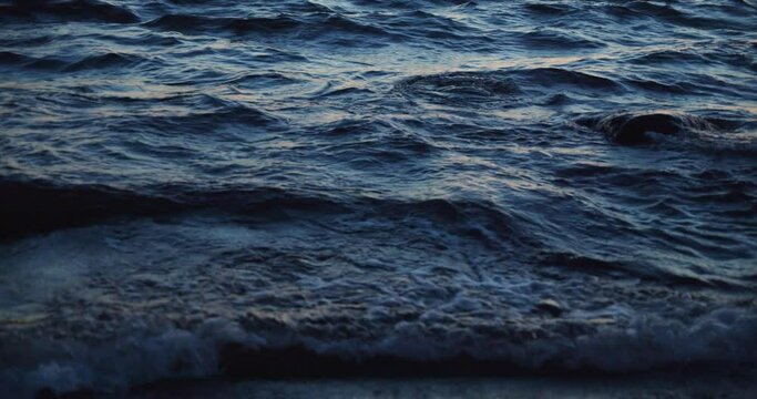 Beautiful blue waves moving, crashing on the sea shore in the dusk.