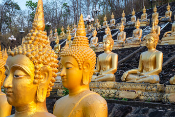 Many small,golden Buddha statues at Wat Phousalao,hilltop temple,reflecting sunset light,overlooking Mekong River,Pakse,southern Laos.
