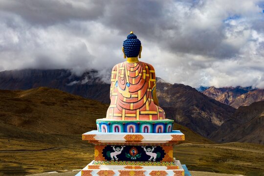 Capture the serene majesty of the Langza Medicine Buddha from behind, gazing towards the awe-inspiring peaks of Spiti Valley, India, at an elevation of 4400 meters.
