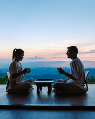 a couple of men and women drinking tea at a Japanese style homestay on vacation in Northern...