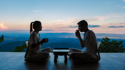 a couple of men and women drinking tea at a Japanese style homestay on vacation in Northern Thailand, staying at a homestay cabin hut in the mountains of Chiang Rai Doi Chang - obrazy, fototapety, plakaty