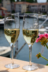 Drinking of French brut champagne sparkling wine in glasses, club party in yacht harbour of Port Grimaud near Saint-Tropez, French Riviera vacation, France