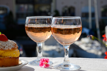 Naklejka premium Wine and cake of French Riviera, glasses of cold rose Cote de Provence wine and Tarte Tropezienne cake in yacht harbour of Port Grimaud, summer vacation in Provence, France.