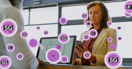 Animation of 5g and symbols in circles over diverse coworkers using laptop and digital tablet - Powered by Adobe