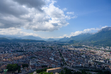 Fototapeta na wymiar View on central part of Grenoble city from Bastille fortres witn mountains around, old cable car, Isere, France