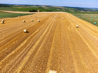 Agriculture in France, yellow haystacks on golden wheat field in July, aerial view, landscape