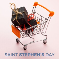 Fototapeta premium Composite of saint stephen's day text and black gift boxes in shopping cart on white background