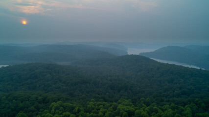 An aerial view of a forest, marsh and lake on a hazy day due to wildfires