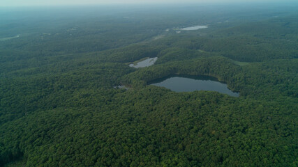 An aerial view of a forest, marsh and lakes on a hazy day due to wildfires